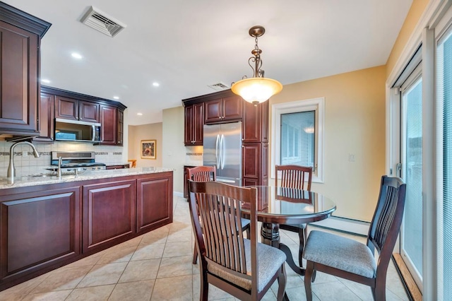 kitchen with visible vents, baseboard heating, stainless steel appliances, and decorative backsplash