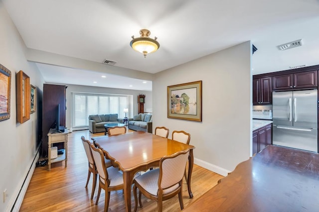 dining area with light wood-style flooring, baseboards, visible vents, and a baseboard radiator