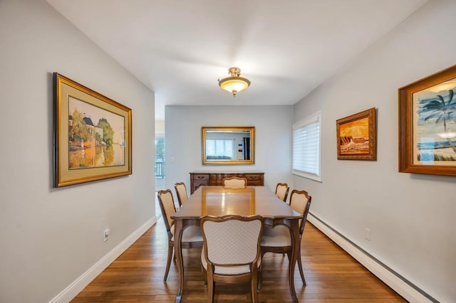 dining space featuring a baseboard heating unit, baseboards, and wood finished floors