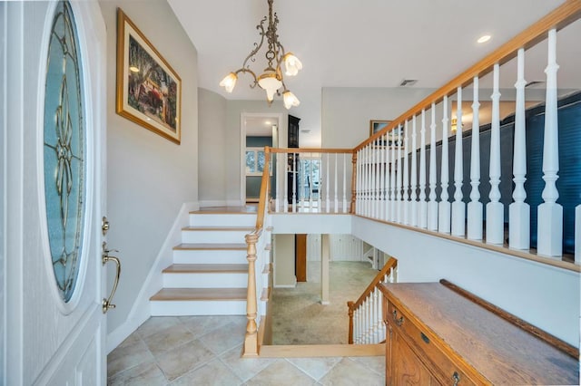 foyer with tile patterned flooring, visible vents, baseboards, stairway, and a notable chandelier