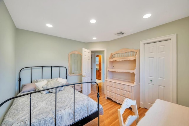 bedroom with a closet, recessed lighting, visible vents, and light wood finished floors