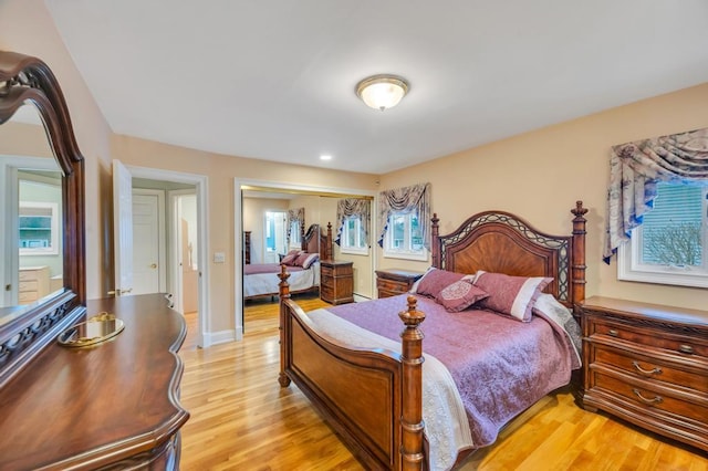 bedroom with baseboards, light wood-type flooring, and a closet