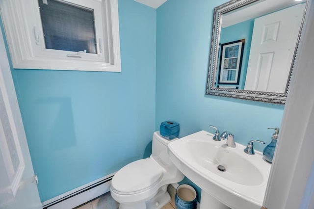 half bath with a sink, a baseboard heating unit, and toilet