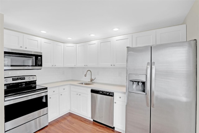 kitchen with a sink, light wood-type flooring, appliances with stainless steel finishes, and light countertops