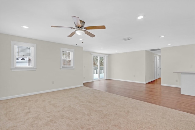 carpeted empty room featuring wood finished floors, baseboards, visible vents, recessed lighting, and ceiling fan