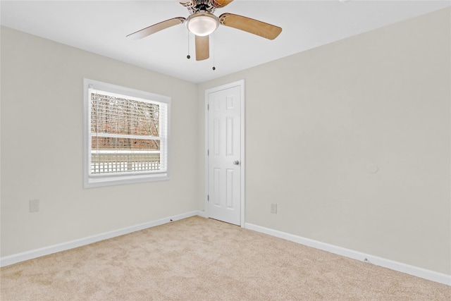 empty room with light colored carpet, baseboards, and ceiling fan