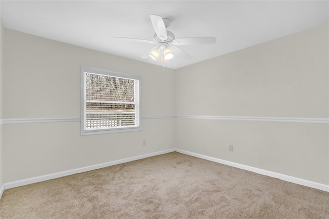 carpeted spare room featuring baseboards and a ceiling fan