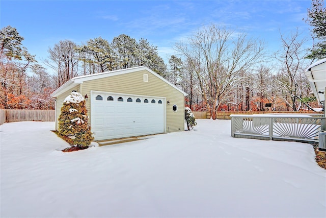 snow covered garage with cooling unit and fence