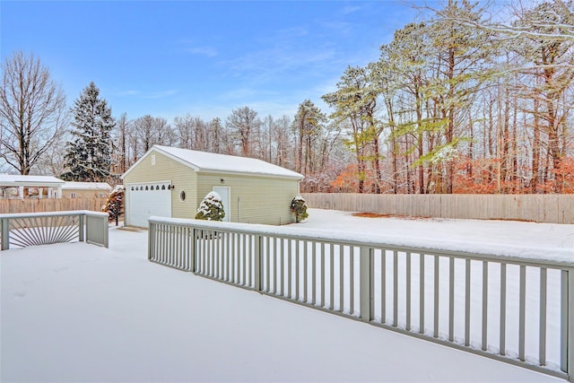 yard covered in snow featuring an outbuilding, fence, and a detached garage