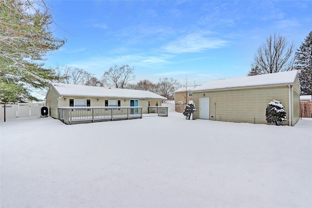 snow covered house with a deck and fence