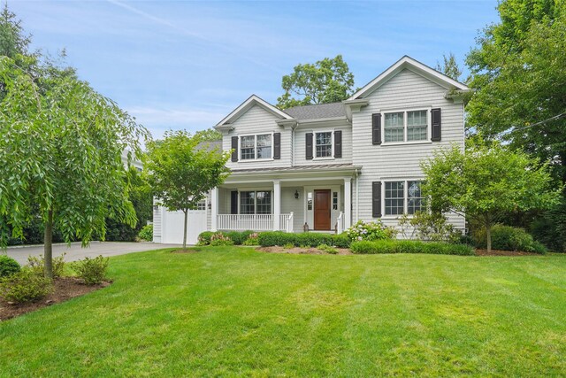 traditional-style home featuring a front lawn, covered porch, and driveway