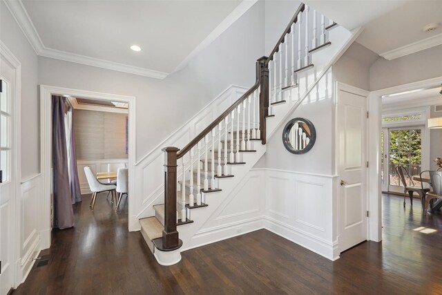 staircase with wainscoting, wood finished floors, crown molding, and a decorative wall