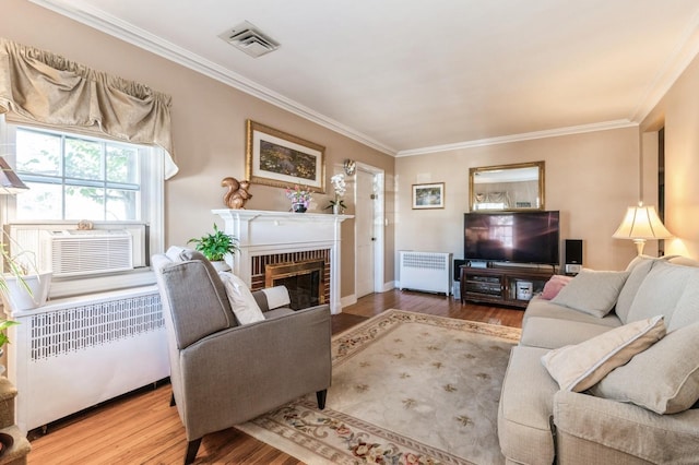 living area featuring visible vents, a brick fireplace, radiator heating unit, and wood finished floors