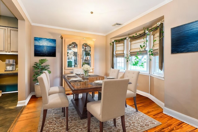 dining room with visible vents, ornamental molding, baseboards, and wood finished floors