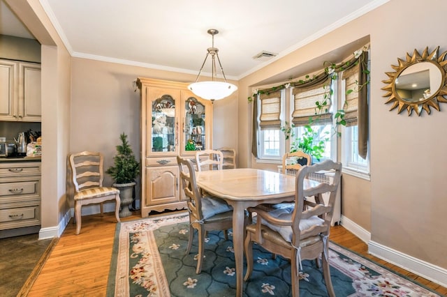 dining area featuring crown molding, baseboards, visible vents, and light wood finished floors