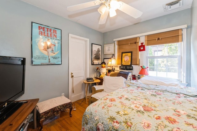 bedroom with wood finished floors, visible vents, and ceiling fan