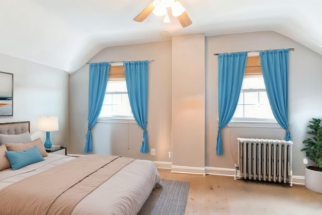 bedroom featuring multiple windows, radiator, and lofted ceiling