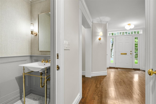 entryway featuring wood finished floors, wainscoting, and crown molding