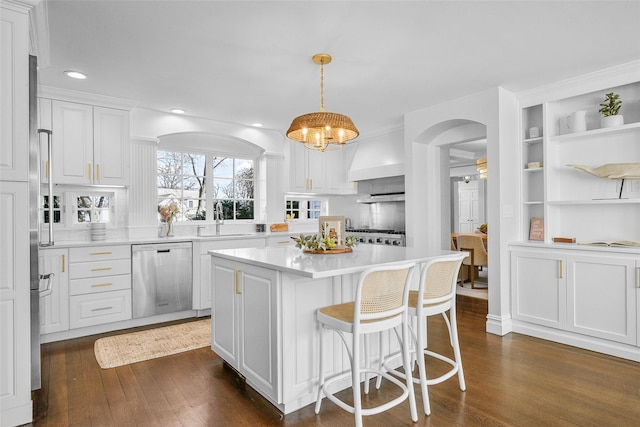 kitchen with arched walkways, a sink, dark wood-type flooring, white cabinets, and appliances with stainless steel finishes