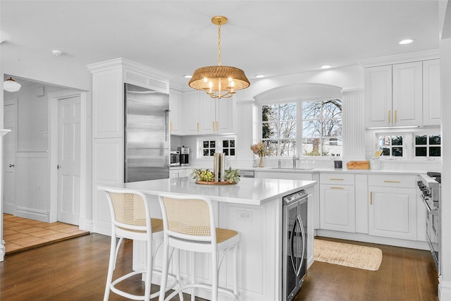 kitchen with dark wood finished floors, white cabinets, built in refrigerator, and a kitchen island