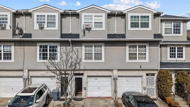 townhome / multi-family property featuring an attached garage, brick siding, and a shingled roof