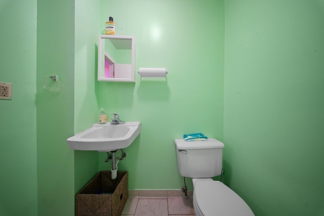 bathroom featuring baseboards, a sink, toilet, and tile patterned floors