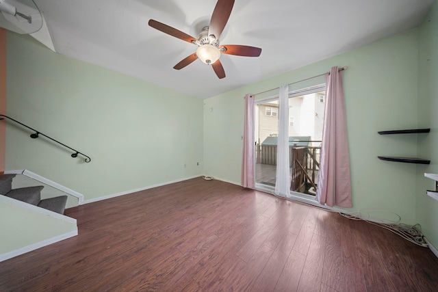 unfurnished living room with a ceiling fan, stairway, baseboards, and wood finished floors