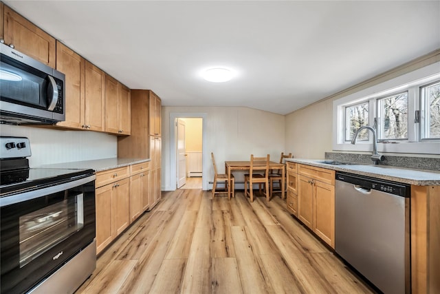 kitchen with appliances with stainless steel finishes, light wood-style floors, a baseboard heating unit, and a sink