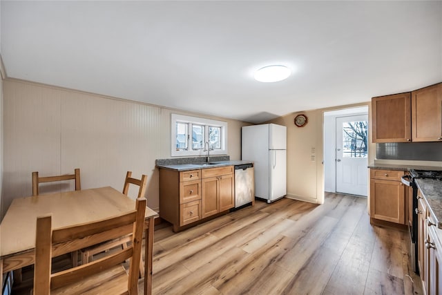 kitchen with brown cabinets, black range with gas stovetop, freestanding refrigerator, light wood-type flooring, and dishwasher