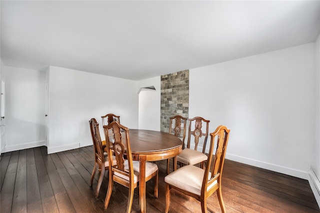 dining room featuring wood-type flooring, arched walkways, and baseboards