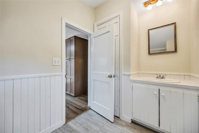 bathroom with a wainscoted wall, wood finished floors, and vanity