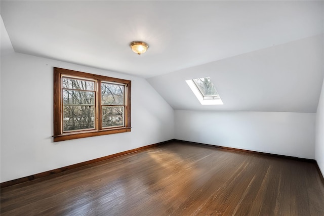 bonus room featuring a healthy amount of sunlight, lofted ceiling with skylight, baseboards, and wood finished floors