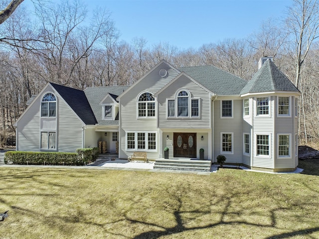 view of front of home featuring entry steps, a front lawn, and roof with shingles