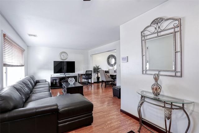 living room with wood finished floors, visible vents, and baseboards