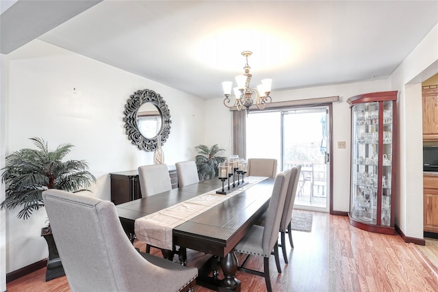 dining area featuring baseboards, light wood-style floors, and an inviting chandelier