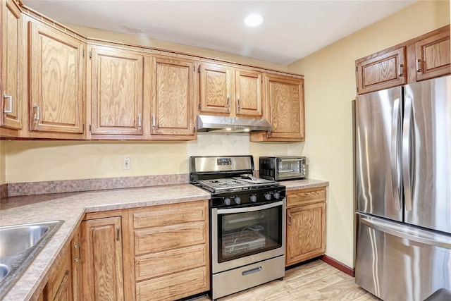 kitchen with light wood finished floors, stainless steel appliances, a toaster, extractor fan, and light countertops