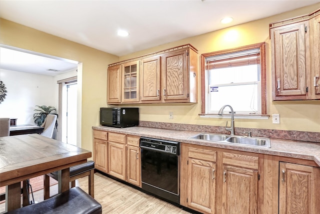 kitchen with glass insert cabinets, light wood-type flooring, recessed lighting, black appliances, and a sink