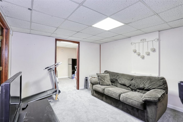 carpeted living area with a paneled ceiling and baseboards