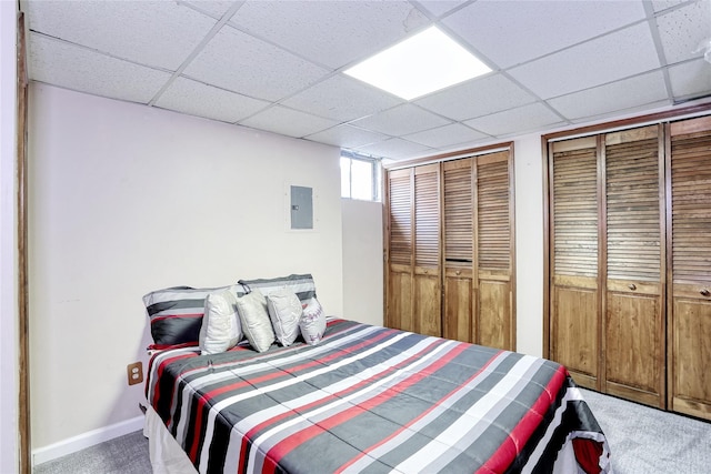 carpeted bedroom with electric panel, a drop ceiling, two closets, and baseboards