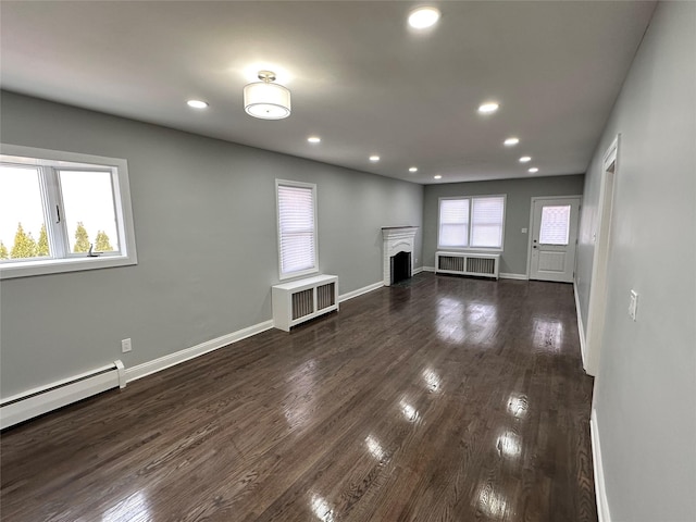 unfurnished living room with dark wood finished floors, a fireplace, and radiator heating unit