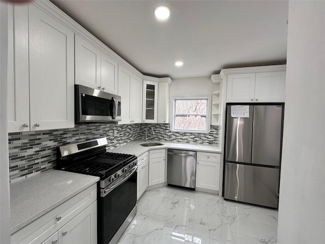 kitchen featuring a sink, open shelves, backsplash, white cabinetry, and appliances with stainless steel finishes