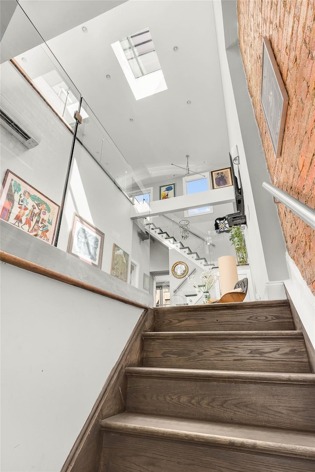 stairway featuring visible vents, a skylight, and a towering ceiling