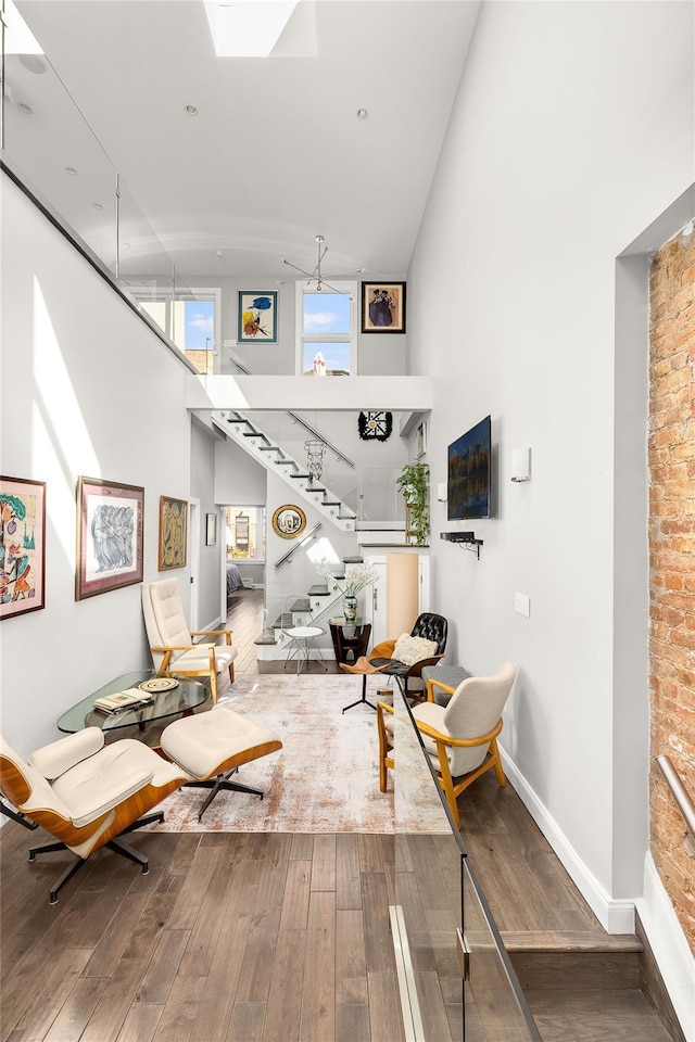 living room with stairway, wood-type flooring, baseboards, and a towering ceiling