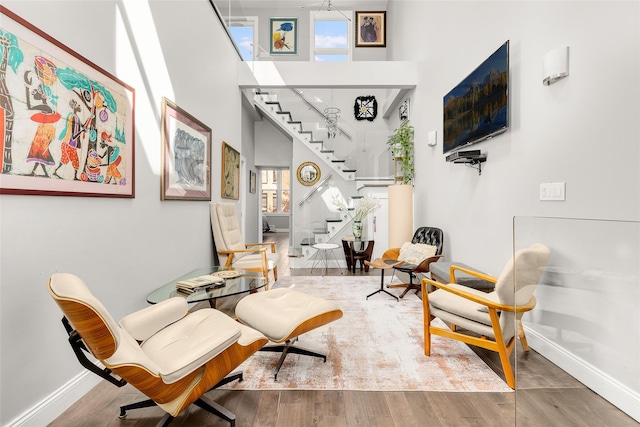 living area with stairs, a high ceiling, baseboards, and wood finished floors