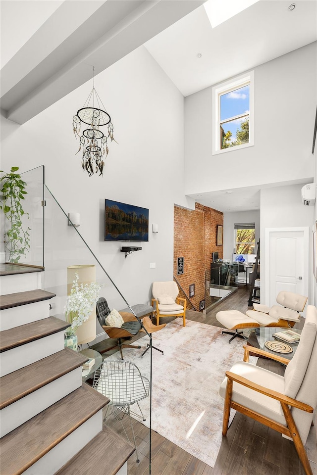 living area featuring wood finished floors, an inviting chandelier, stairs, an AC wall unit, and a towering ceiling