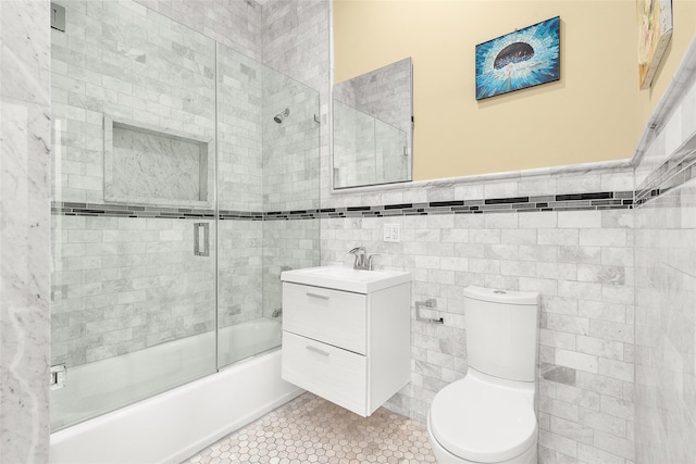 full bathroom featuring vanity, shower / bath combination with glass door, tile patterned flooring, tile walls, and toilet