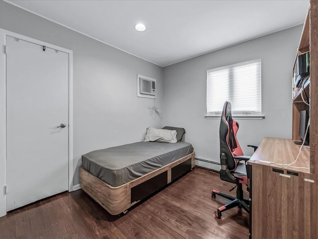 bedroom featuring a baseboard heating unit, an AC wall unit, and wood finished floors