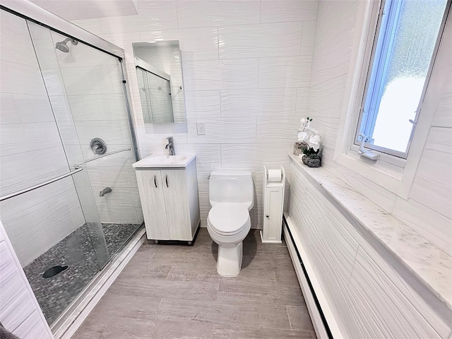 full bath with vanity, wood finished floors, a shower stall, toilet, and baseboard heating