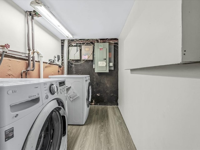 laundry room featuring electric panel, wood finished floors, and washing machine and clothes dryer