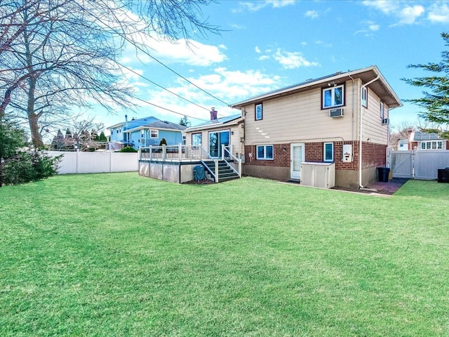 back of house featuring a wooden deck, a lawn, a fenced backyard, and brick siding